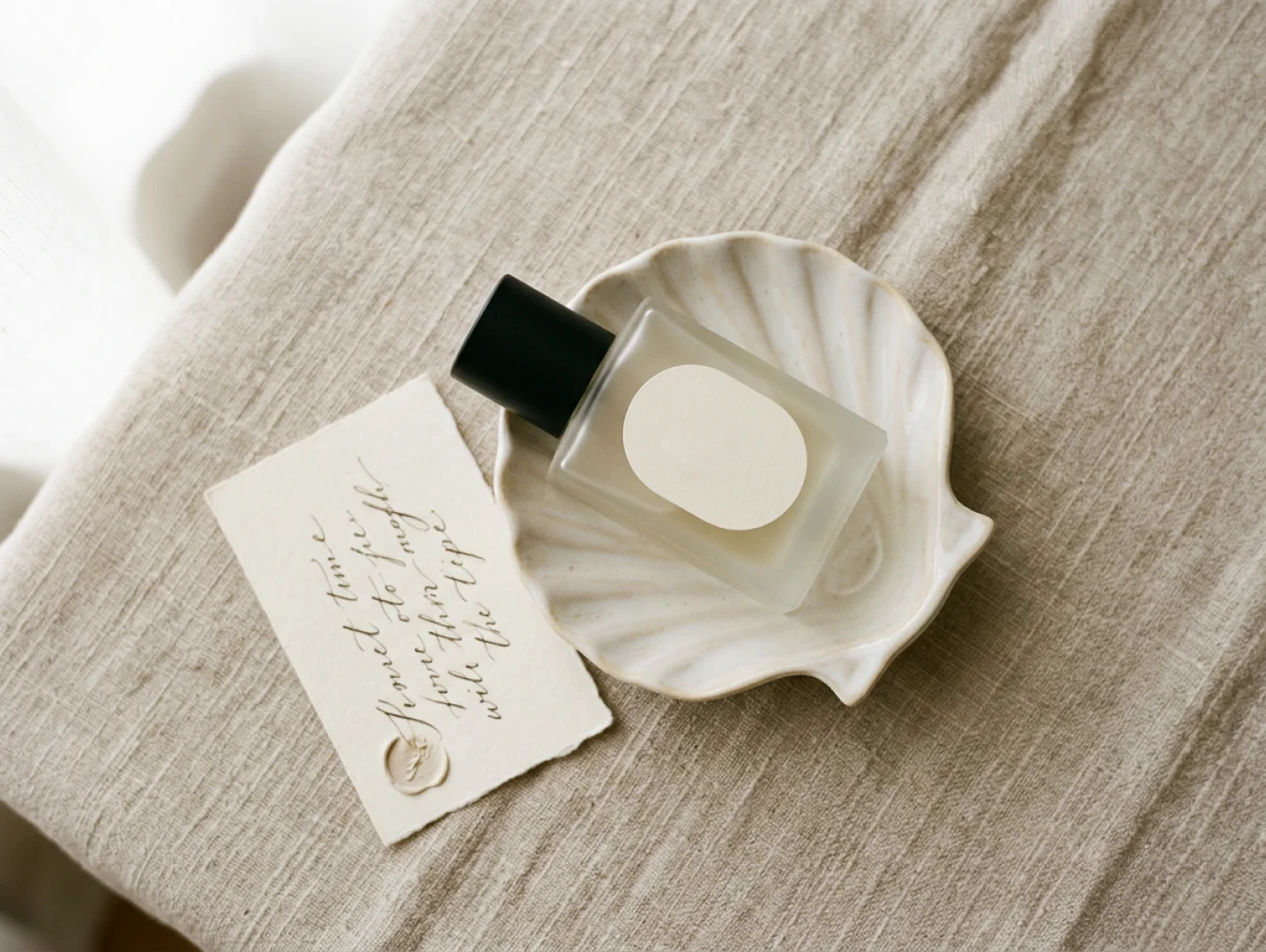 A Fieldnote bottle resting in a shell-shaped dish beside a handwritten card